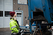 Young female construction worker operating machinery