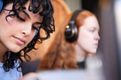 Female woman with cool eyeliner make up looking away while listening to podcast or music in headphones