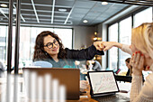 Smiling woman giving fist bump to colleagues in office