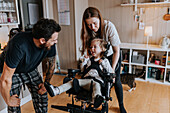 Parents with disabled child in wheelchair at home