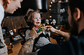 Parents playing with smiling disabled child in wheelchair