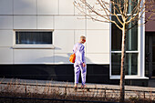 View of young woman skateboarding, modern building in background