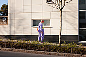 View of young woman skateboarding, modern building in background