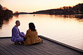 Young female gay couple sitting and talking at river
