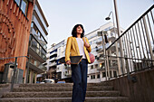 Flacher Blick auf eine Frau, die eine Treppe hinuntergeht und ein Skateboard trägt