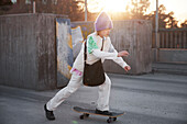 Blick auf ein skateboardfahrendes Mädchen, im Hintergrund scheint die Sonne