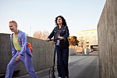 Junge Frauen auf dem Skateboard und auf dem Roller