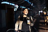 Blick auf eine Frau mit Einwegbecher am Bahnhof