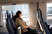Mittlere erwachsene Frau im Zug bei der Nutzung eines Laptops