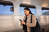 Mittlere erwachsene Frau am Bahnhof benutzt Mobiltelefon