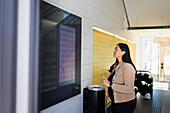 Frau im Bahnhof schaut auf die Ankunfts- und Abfahrtstafel auf dem Bildschirm