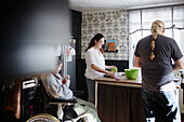 Eltern mit behinderter Tochter im Rollstuhl bei der Essenszubereitung in der Küche