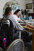 Father and disabled teenage girl sitting and dining table and having meal