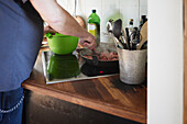 Mid section of man frying meat on frying pan