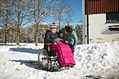 Mother talking to teenage daughter on wheelchair during winter walk