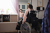 Behindertes Mädchen im Teenageralter im Rollstuhl vor einem Spiegel
