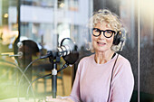 Reife Frau sitzt und moderiert Podcast oder Radiosendung oder Podcast