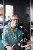 Reifer Mann sitzt und moderiert Podcast oder Radiosendung oder Podcast