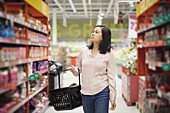 Woman looking at prices during inflation while doing shopping in supermarket