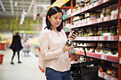 Frau schaut beim Einkaufen im Supermarkt auf die Preise während der Inflation