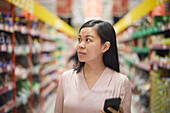Frau schaut beim Einkaufen im Supermarkt auf die Preise während der Inflation