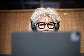 Ältere Frau mit Kopfhörern am Tablet