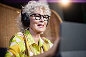 Ältere Frau mit Kopfhörern und Tablet