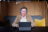 Älterer Mann mit Kopfhörern und Tablet