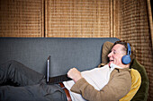 Senior man in headphones having video call on tablet