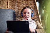 Älterer Mann mit Kopfhörern bei einem Videoanruf auf einem Tablet
