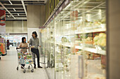 Pärchen im Supermarkt im Gespräch vor Kühlschränken mit Gemüse