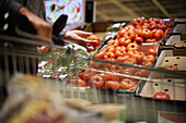 Customer's hand holding beefsteak tomato in store