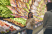 Blick auf ein Paar, das in einem Supermarkt steht und sich beim Aussuchen von Äpfeln unterhält
