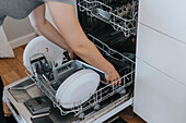 Woman putting dirty dishes in dishwasher