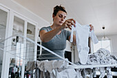 Pregnant woman doing housework and hanging baby clothes on drying rack