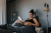 Schwangere Frau entspannt sich im Bett und liest ein Buch