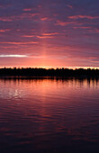 The coastline of islands near Helsinki, at sunset, a red glow in the sky. 