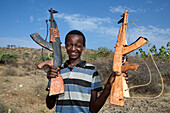 Junge verkauft Holzgewehre