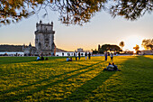 Menschen genießen den Belen-Turm-Garten (Jardim da Torre de Belem) bei Sonnenuntergang, Lissabon, Portugal