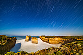 Orion (right) and Sirius (upper right) setting into the west over Loch Ard Gorge on the Great Ocean Road, Victoria, Australia, with illumination from the rising Moon a day past full behind the camera to the east.