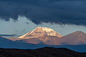 Sonnenaufgangslicht beleuchtet den schneebedeckten Vulkan Tupungato in den Anden in der Provinz Mendoza, Argentinien.