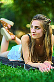 Portrait of a young beautiful caucasian woman in her 20s lying on the grass in a garden. Lifestyle concept.