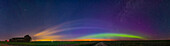 Ein 150°-Panorama eines Bogens diffuser Aurora im Nordosten und über dem Glühen der Sonnenwende-Dämmerung im Norden in der Mitte, während das städtische Himmelsglühen von Calgary den Himmel links im Westen erhellt, ebenso wie ein seltsames Wolkenband, das den ganzen Abend über im Norden anhielt.