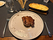 A ribeye steak with potatoes au gratin on the side in a restaurant in San Rafael, Argentina.