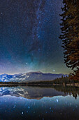 The autumn constellations of Perseus and Cassiopeia above, with bright Capella in Auriga and the Pleiades star cluster in Taurus, at bottom, rising in the northeast over Lake Edith in Jasper National Park, on a clear autumn night. The Double Cluster is at centre, above the larger group of stars around Mirfak called the Perseus Association.