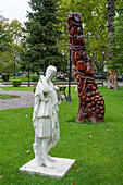 Eine Marmorstatue und eine aus einem stehenden toten Baumstamm geschnitzte Skulptur auf der Plaza San Martin in San Rafael, Argentinien.