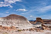 A sandstone caprock on a clay hoodoo in the bentonite hills of the Caineville Desert near Hanksville, Utah with the Henry Mountains behind.