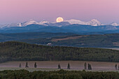 ull Moon setting over Rocky Mountains, taken from Rothney Astrophysical Observatory on August 28, 2007, night of total eclipse of the Moon. Umbral eclipse was over by moonset though the Moon was still in penumbral eclipse. Taken with Canon 20Da camera and 135mm lens at ISO800 and f/4.5 for 1/160 sec. Moon in blue of Earth's shadow on atmosphere.