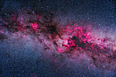 A framing of the major areas of bright and dark nebulosity in Cygnus and Cepheus, showing pink emission nebulas contrasting with dark dusty regions in the Cygnus and into the Perseus arms of the Milky Way. Cepheus is at upper left; northern Cygnus is at right, with the bright Cygnus starcloud right of centre. The reddening (or yellowing) effects of interstellar dust in the spiral arms of the Milky Way is apparent.
