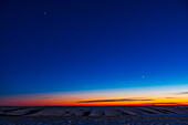 The line-up of three evening planets in the southwest twilight sky, on December 17, 2021 — with Jupiter at top left, Venus at bottom right, and dimmer Saturn in the middle, all defining the line of the ecliptic in the cold winter sky this night. The stars of Capricornus are at centre.